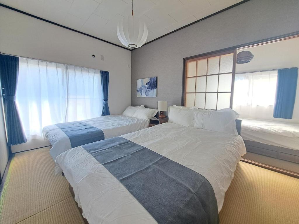 a hotel room with two beds and a window at 不入斗-横須賀の大型一棟貸し-最大25人-家族団体向け in Yokosuka