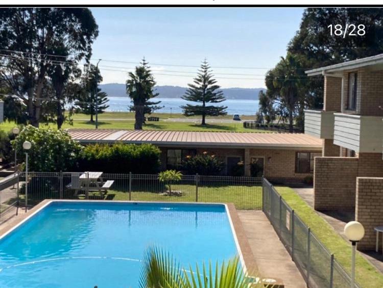 a large blue swimming pool in front of a house at Beach front apartment in Batemans Bay