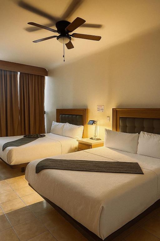 托雷翁Hotel Grand Lion的配有吊扇的酒店客房内的两张床