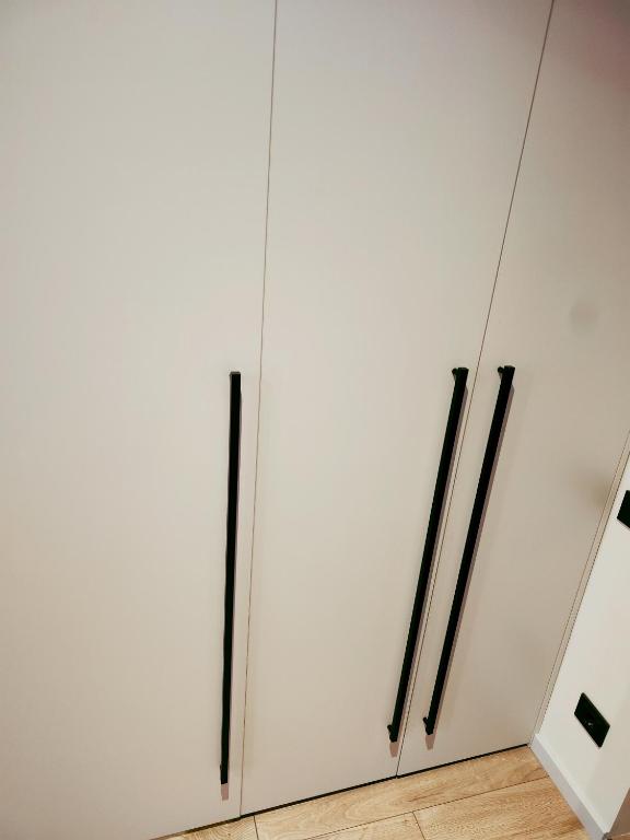 a white wardrobe with black handles in a room at Apartamentai šalia miesto centro in Telšiai