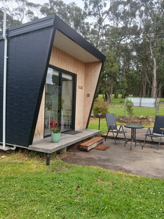 a black tiny house with a table and chairs at Berry World in Timboon