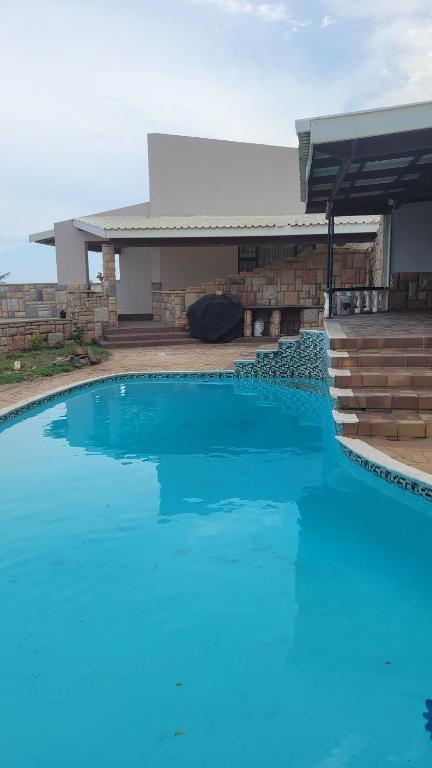 a blue swimming pool in front of a house at Sharks View in Port Shepstone