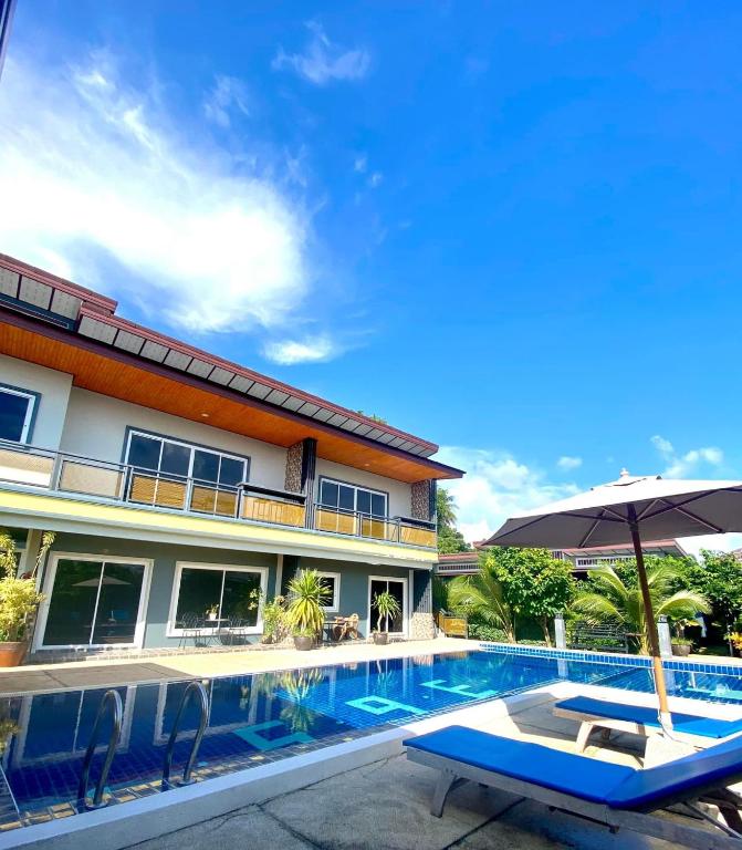 a swimming pool with an umbrella and a chair next to a house at 365 Place Maikhao in Ban Mai Salae