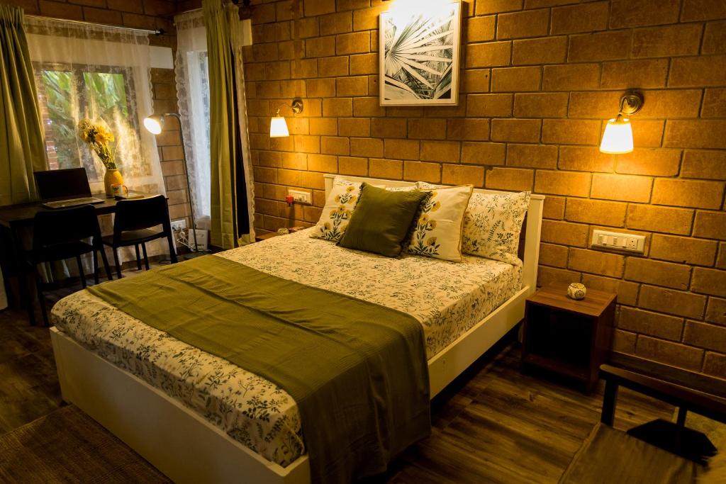 une chambre avec un lit et un mur de briques dans l'établissement Happy Haven Farmstay, à Mangalore