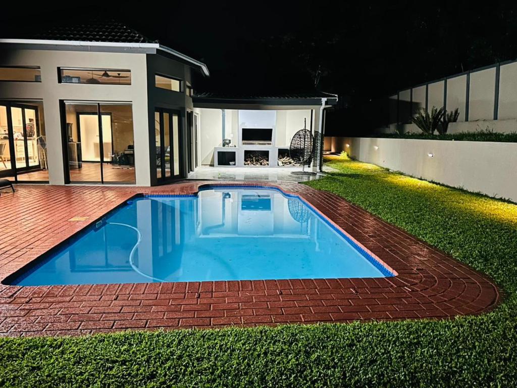 a swimming pool in the yard of a house at night at Alwande's Guesthouse in Richards Bay