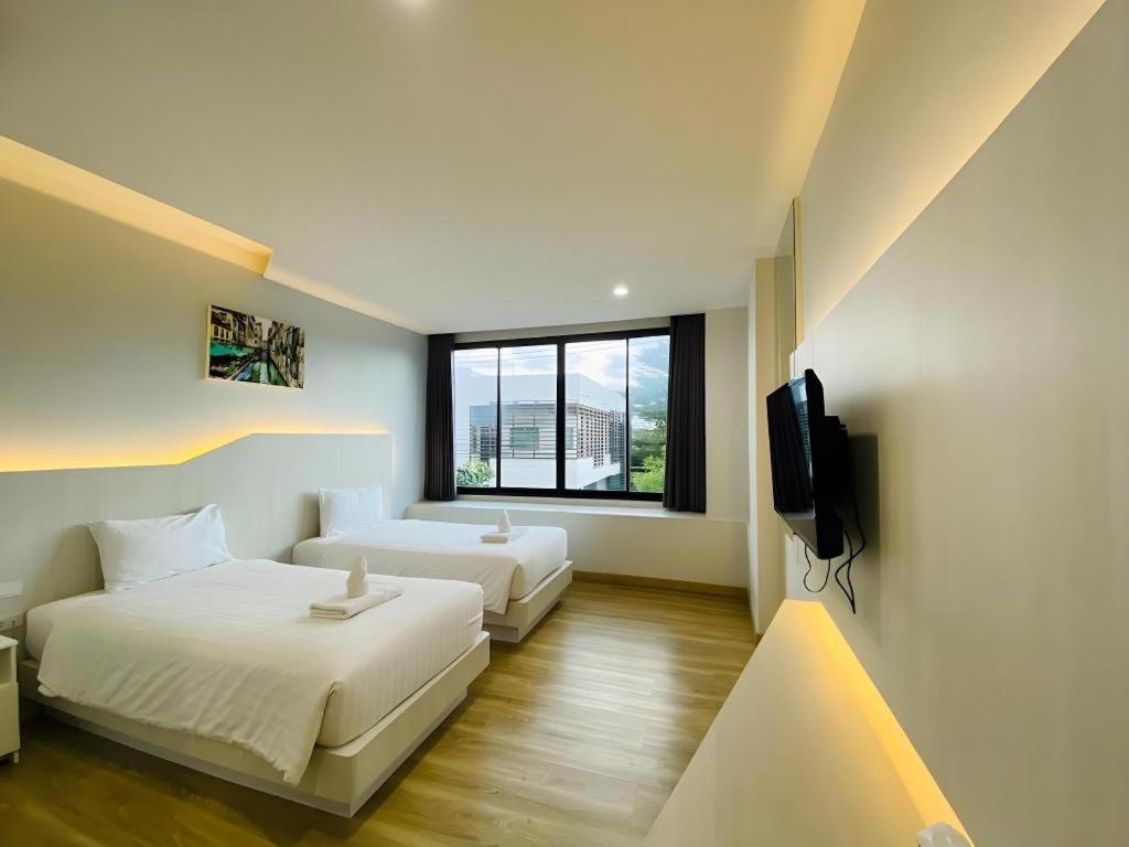 a hotel room with two beds and a television at Luxsna Residence in Ban Kohong