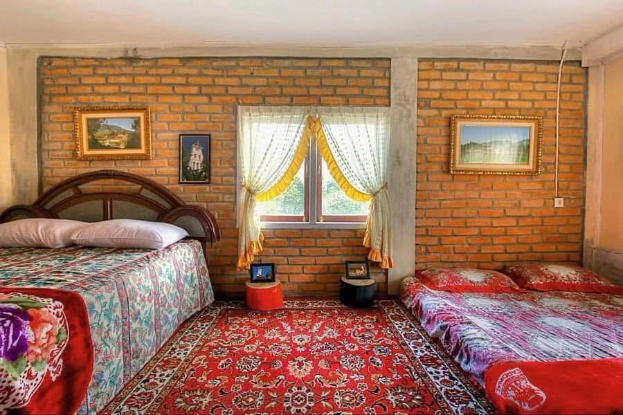 a bedroom with two beds and a brick wall at Elle Maya Sari in Kotabaru