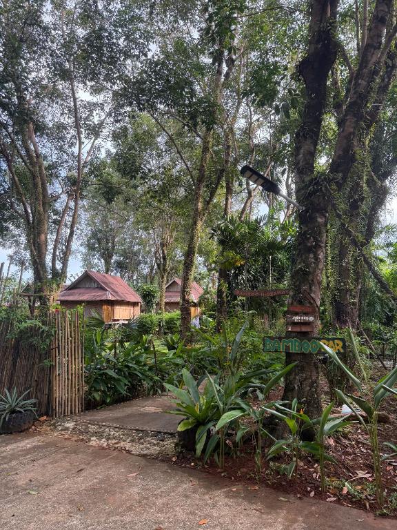 a garden with a tree and a house in the background at Bamboo Hideaway Resort in Ko Mak