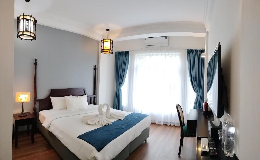 Khách Sạn Thủ Đô Formerly Impressive Hotel في هانوي: غرفة نوم بسرير كبير مع ستائر زرقاء
