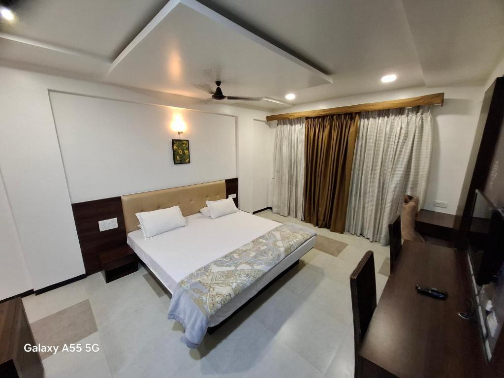 a bedroom with a bed and a large window at Hotel Pride Executive in Satara