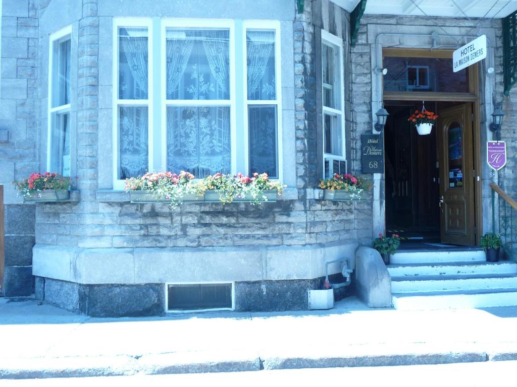 a building with two windows and flowers in front of it at La Maison Demers in Quebec City