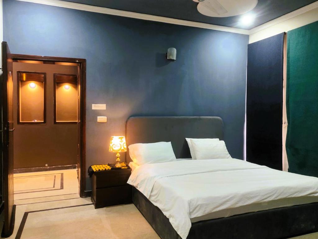 een slaapkamer met een bed en een blauwe muur bij Pinewood Guest House in Islamabad