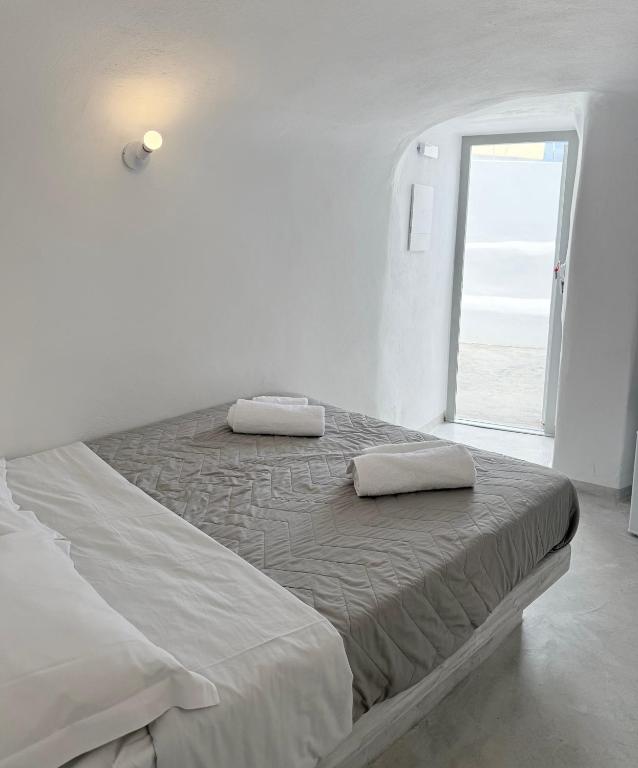 a white bedroom with a large bed with a window at Fira Heart Studios in Fira