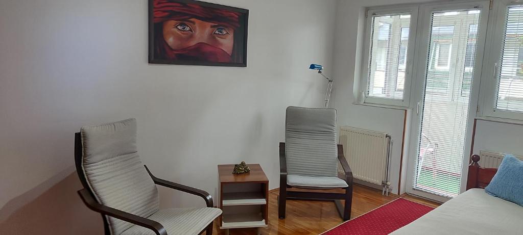 a living room with two chairs and a painting on the wall at HushHush Apartman in Belgrade