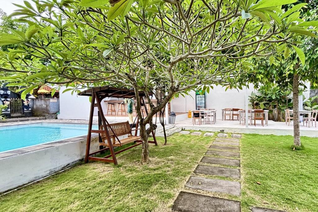 a tree with a swing next to a pool at Casa Komala Uluwatu in Uluwatu