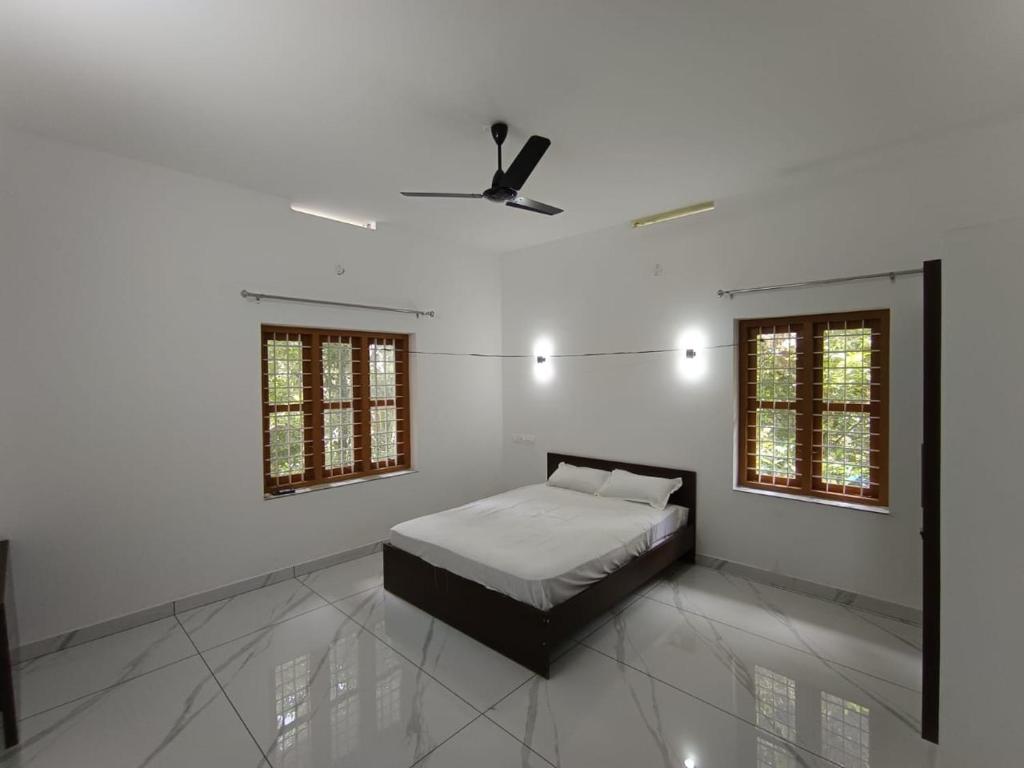 een slaapkamer met een bed en een plafondventilator bij Aathira Agri Homes in Trichūr