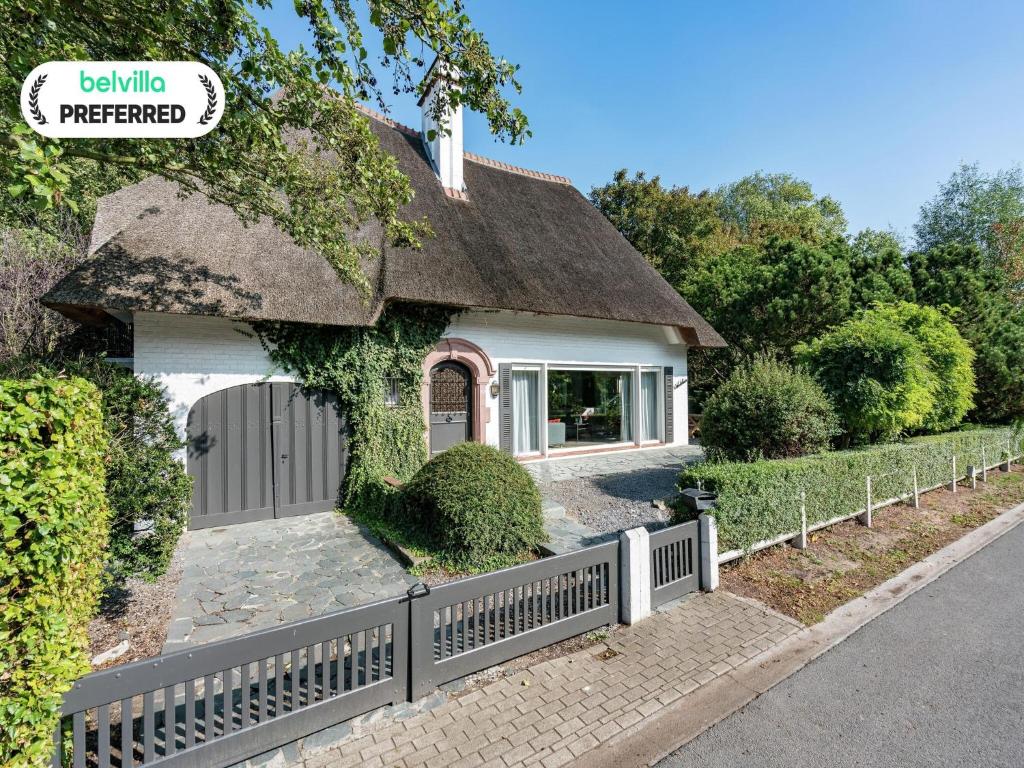 een wit huis met een hek en een hek bij Oostduinkerke Forestside Villa in Oostduinkerke