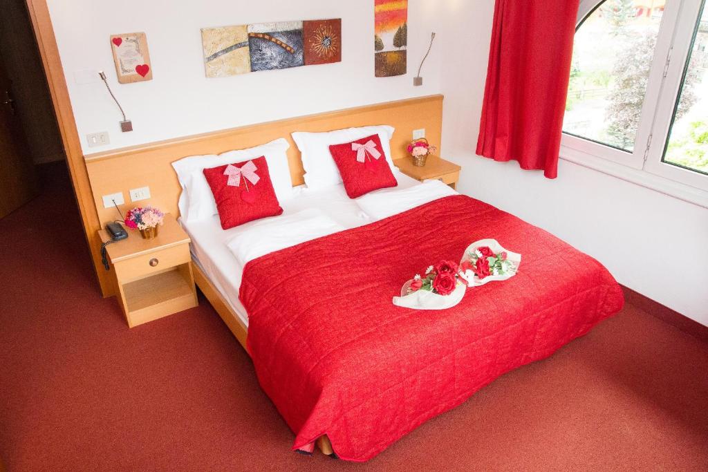 a bedroom with a red bed with two trays on it at GH Hotel Piaz in Pozza di Fassa