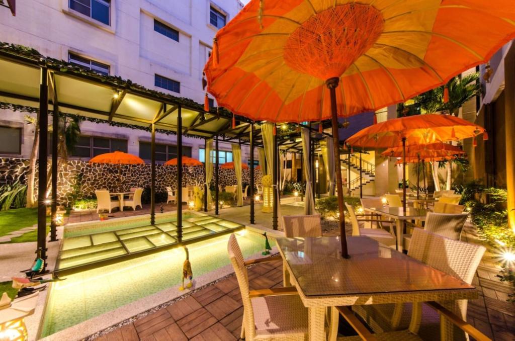 Un patio con mesas y sombrillas en un edificio. en 嬉安平 Si Anping by Hotel Si, en Tainan