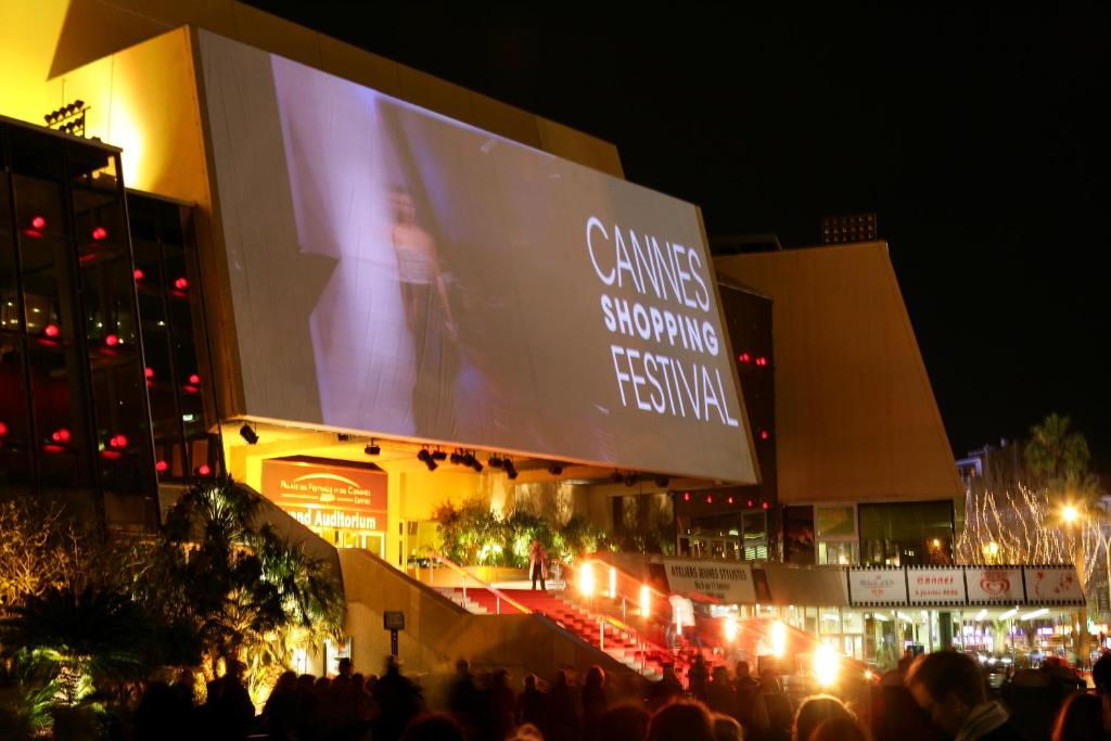 Une foule de personnes debout devant un bâtiment la nuit dans l'établissement Appartement proche mer et gare, à Cannes