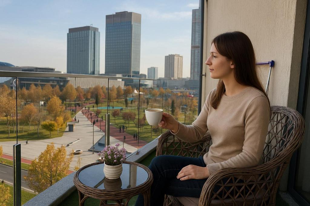 Una mujer sentada en un balcón sosteniendo una taza de café. en Tashkent Park View Suites - ApartmentHotels uz, en Tashkent