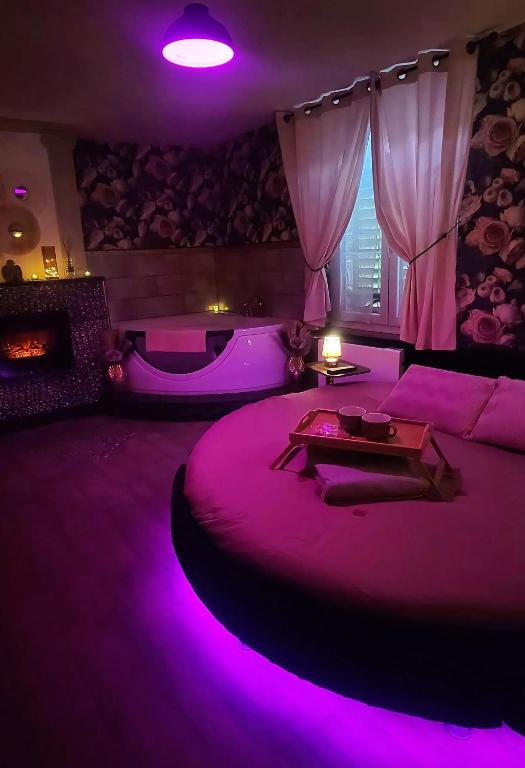 a purple room with a bed with a table on it at L'atelier des rêves, balnéo, lit rond, centre-ville in Lunéville