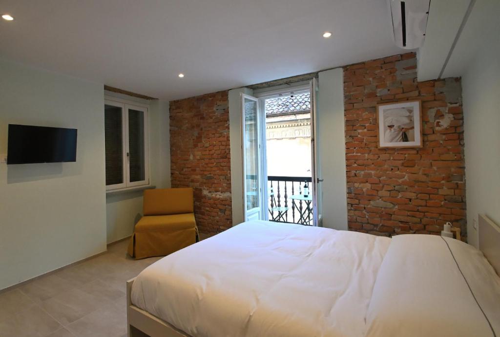 Casa PORTA LANERO di Francesco e Alessandro في نيتسا مونفيراتو: غرفة نوم بها سرير كبير وجدار من الطوب