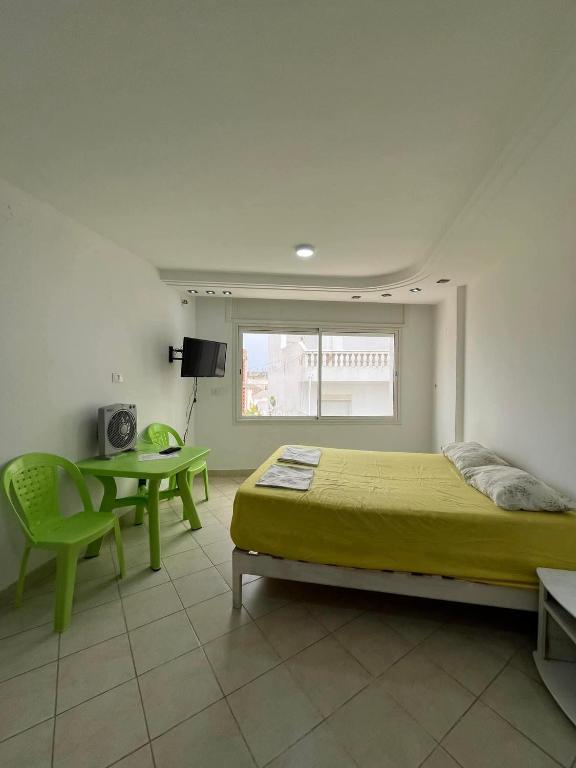 a bedroom with a bed and a table and a window at Studio à louer - Kélibia centre ville in Kelibia