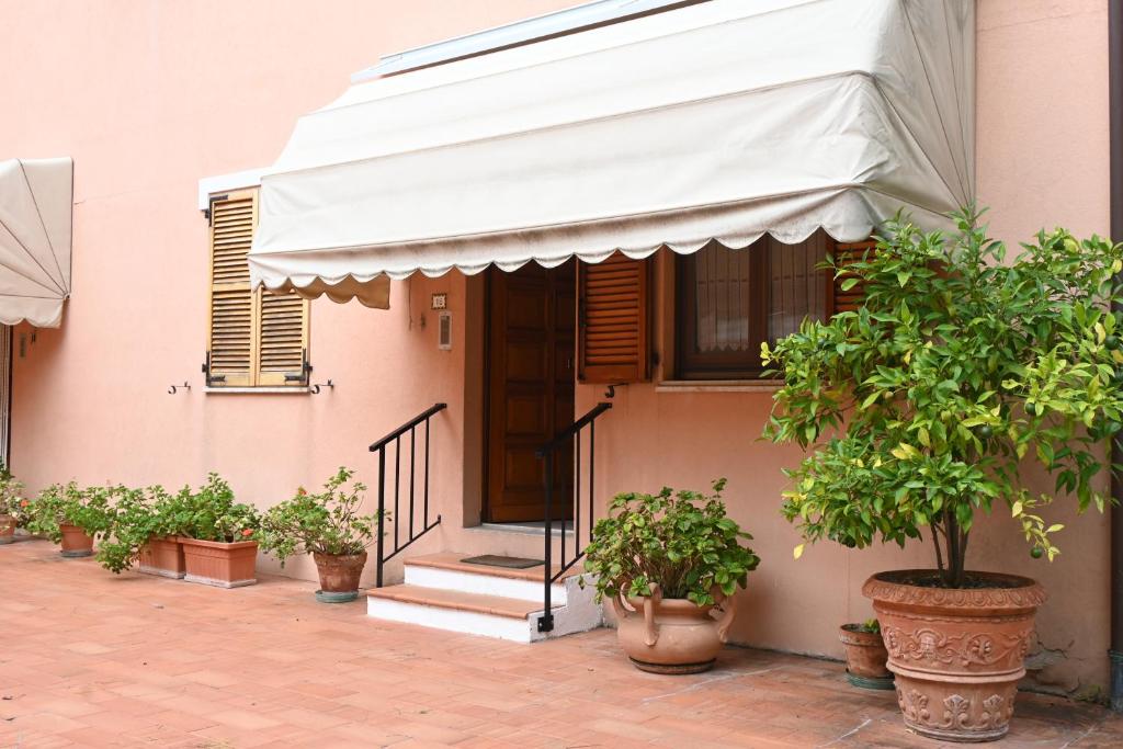a pink house with awning and potted trees in pots at Bilocale con balcone a Numana - N080 in Sirolo