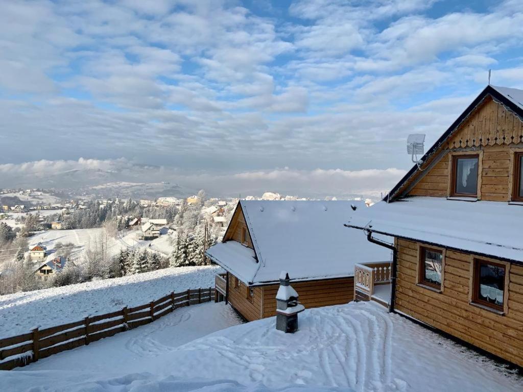 a log cabin in the snow with a roof at Osada Na Ochodzitej in Koniaków