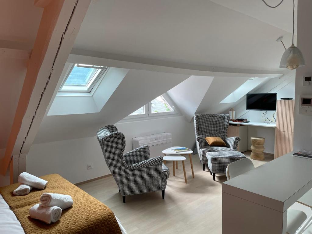 een zolderkamer met een bed, stoelen en een bank bij Studio Lestal in Aix-les-Bains