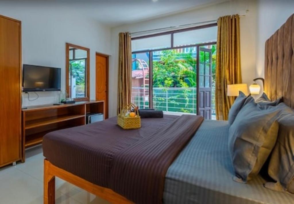 Un dormitorio con una cama grande y una ventana grande. en Hotel Sky Blue Baga Goa, en Baga