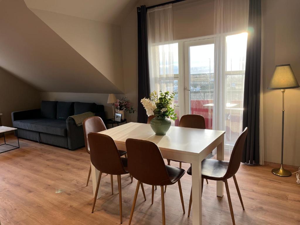 una sala de estar con una mesa, sillas y un sofá en Hvammur Apartments by the Harbour, en Höfn