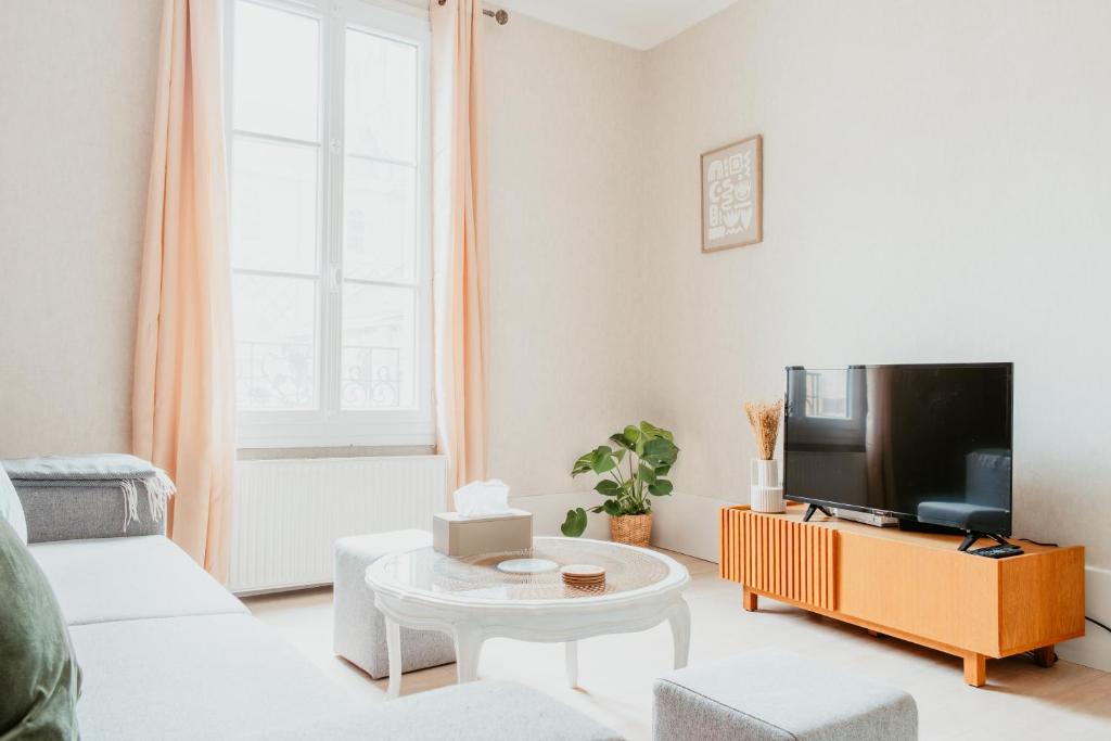 Una sala de estar con un sofá y un televisor. en À 2 Pas de la Plage Cosy et Super Équipé, en Le Havre