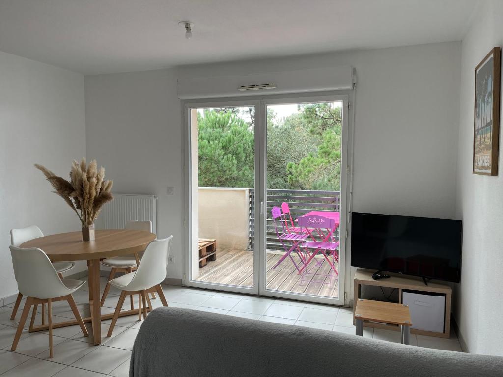 een woonkamer met een eettafel en een televisie bij Labenne Océan in Labenne