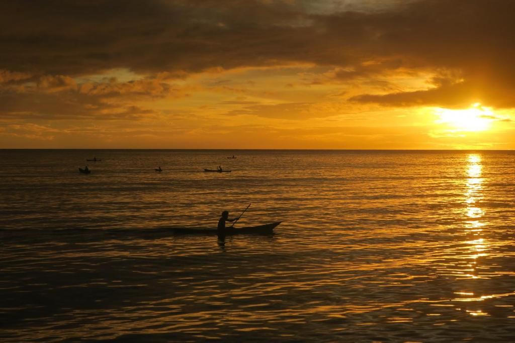 una persona en un barco en el océano al atardecer en Zaru Hotel, en Gizo