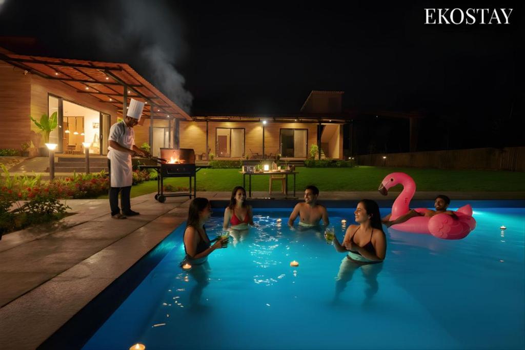 Casa Vayu 3 BHK - EKOSTAY في لونافالا: مجموعة من الناس في مسبح في الليل