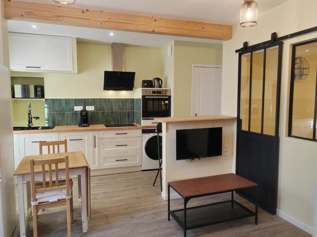 a kitchen with white cabinets and a table and a tv at L'Atelier ,Calme, parking, centre Gémozac in Gémozac