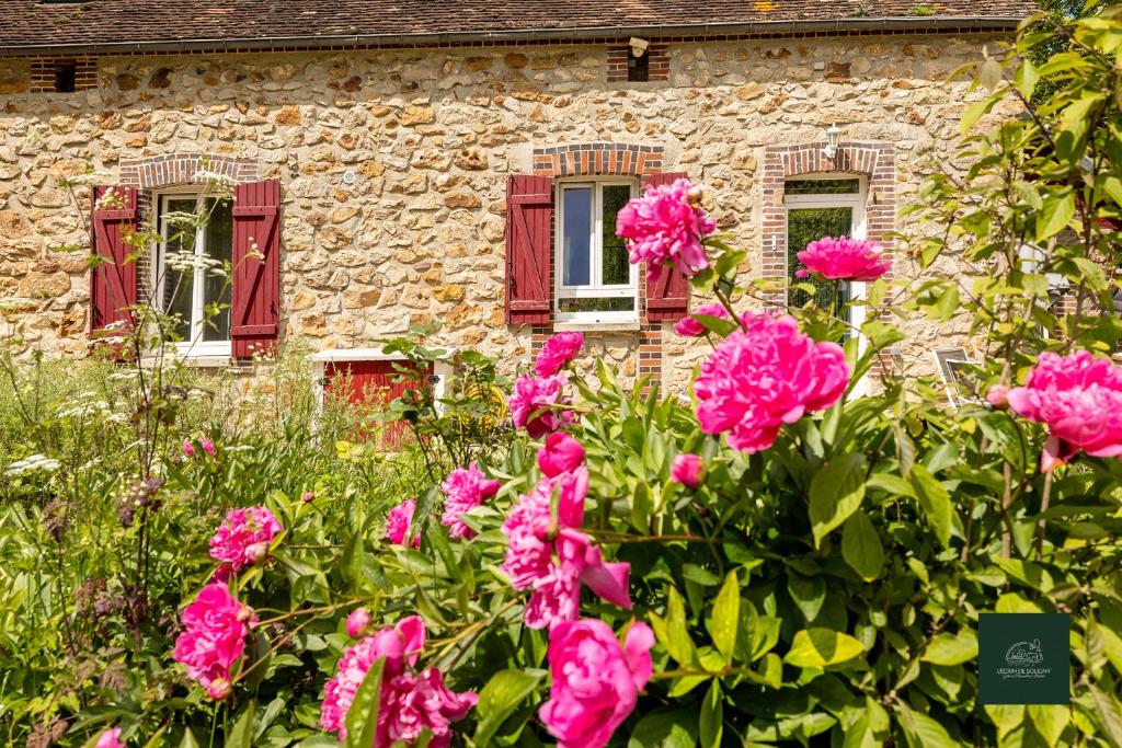 a stone house with pink flowers in front of it at L'Ecrin de Soligny in Soligny-les-Étangs