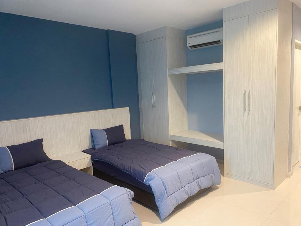a bedroom with two beds with blue walls and a closet at IRONMAN HomeStay in Lumut