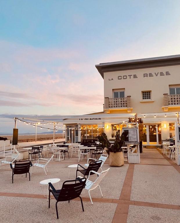 a group of chairs and tables in front of a building at HOTEL RESTAURANT LA COTE REVEE in Leucate