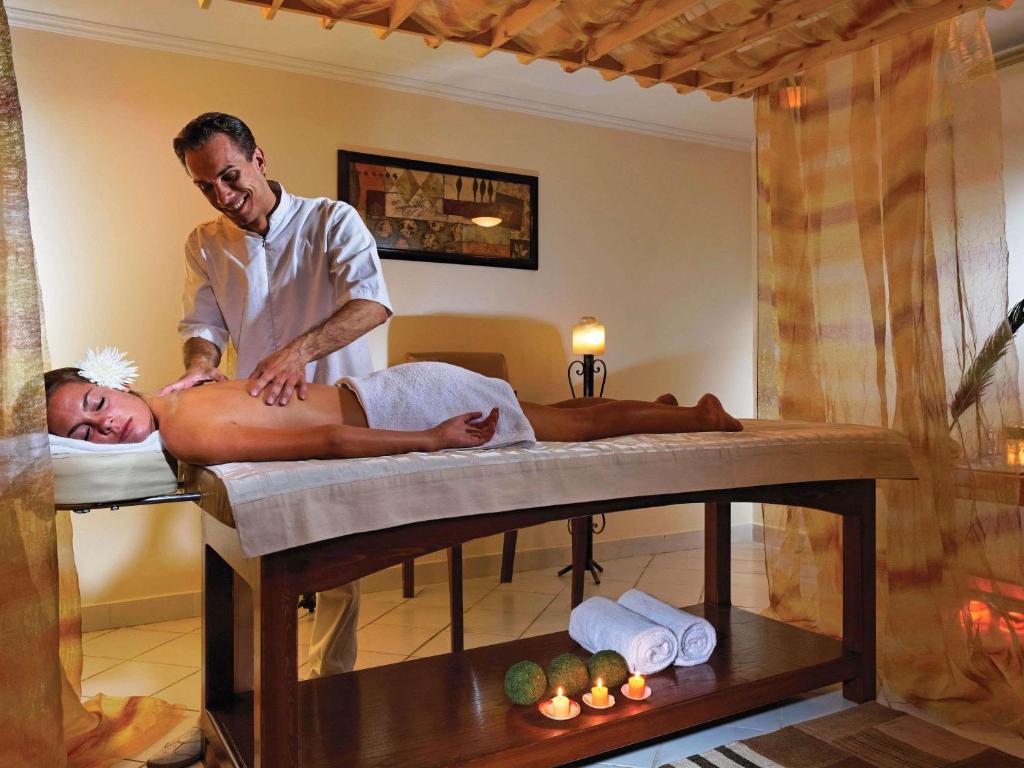 a man giving a man a massage in a bed at Movenpick Taba Resort & Spa in Taba