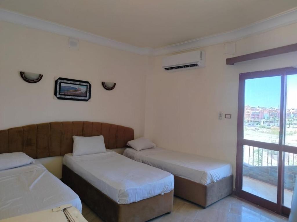 two beds in a room with a window at Eiffel Hotel Hurghada in Hurghada