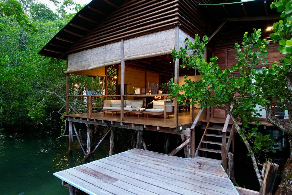 a wooden house on a pier with a table and stairs at Villa Luzo & Tours in Saonek