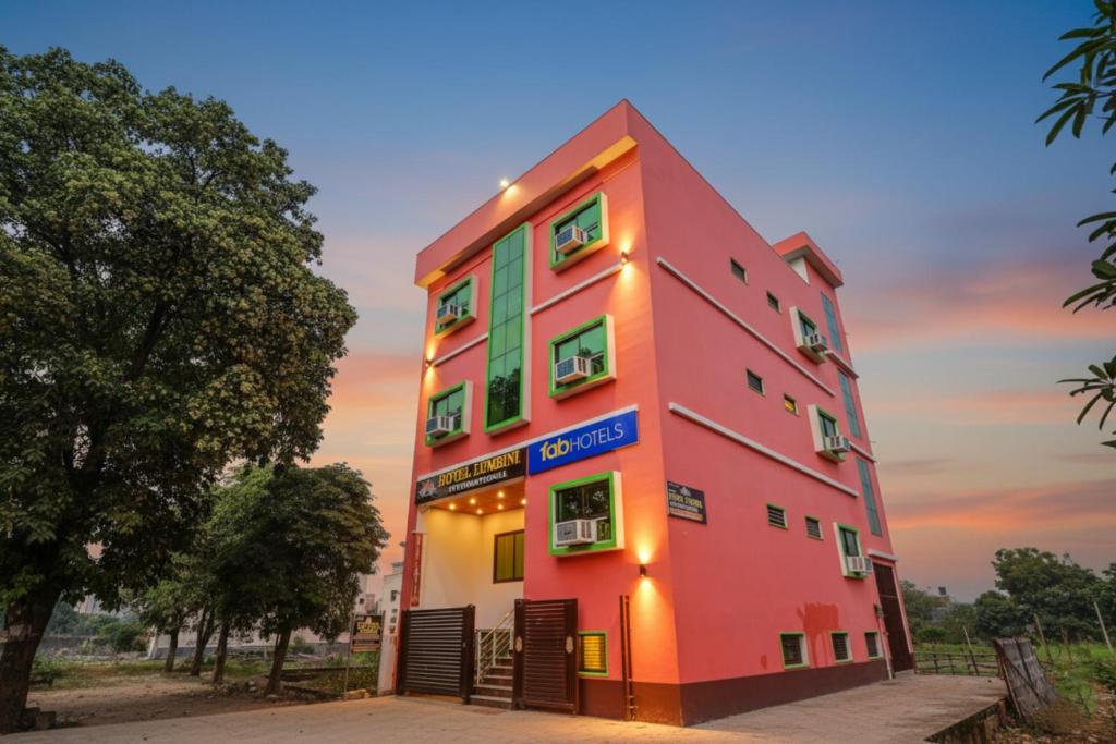 a pink building with a blue sign on it at FabHotel Lumbini International - Nr Sarnath Museum in Varanasi
