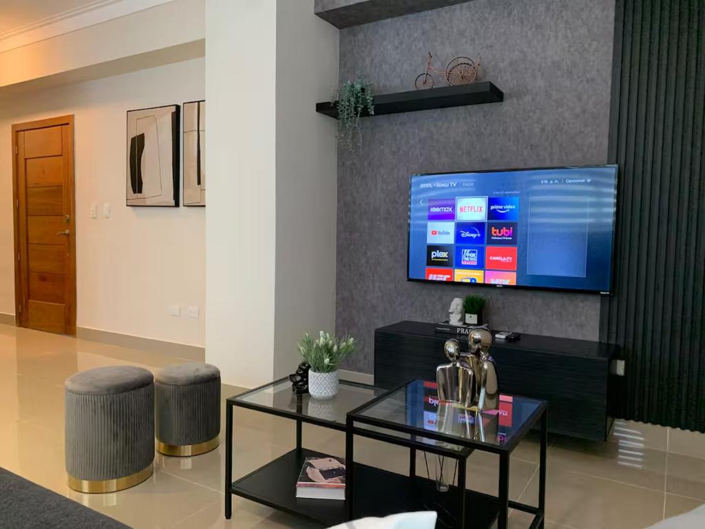 Departamento en Santo Domingo في سانتو دومينغو: غرفة معيشة مع تلفزيون وطاولة وكراسي