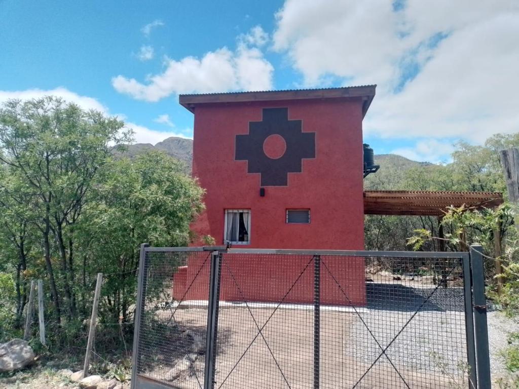een rood gebouw met een zwart kruis erop geschilderd bij La Chakana in Capilla del Monte