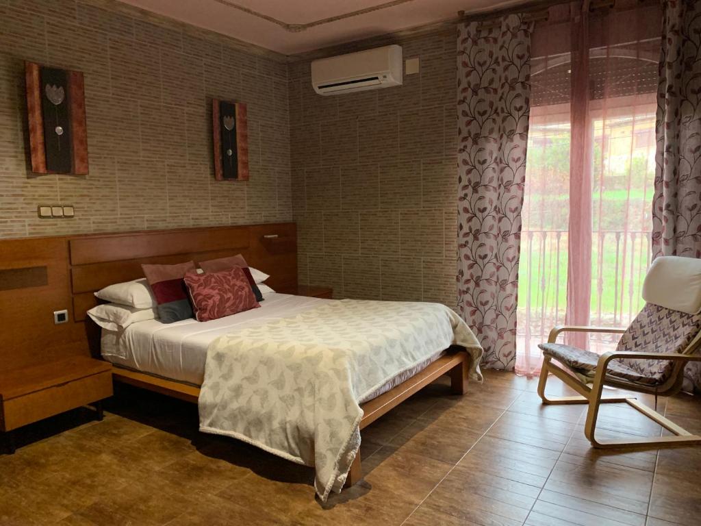 Un dormitorio con una cama y una silla y una ventana. en Apartamento rural FRAGARIA, en Casas del Monte