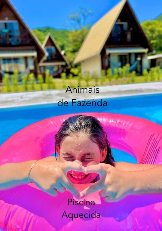 a woman laying in a pool in a pink raft at Villa Park Chalés - A sua fazendinha ao lado do Beto Carrero in Penha