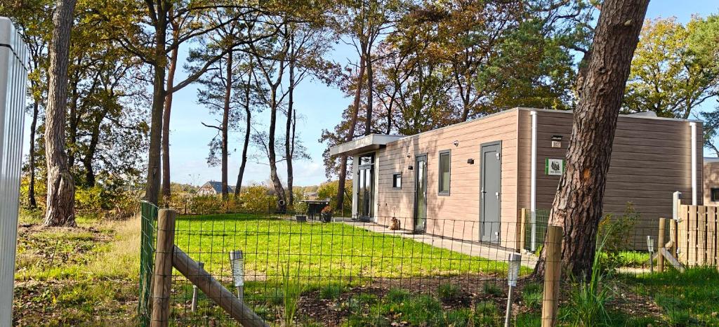 ein kleiner Schuppen auf einem Feld mit einem Zaun in der Unterkunft casa kwispel genieten met uw hond in de natuur in Haarle